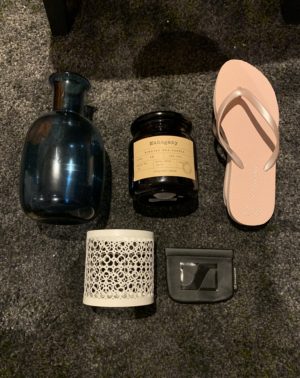 Blue vase, black candle, flip flops, candle holder and headphone pouch flat lay on carpet